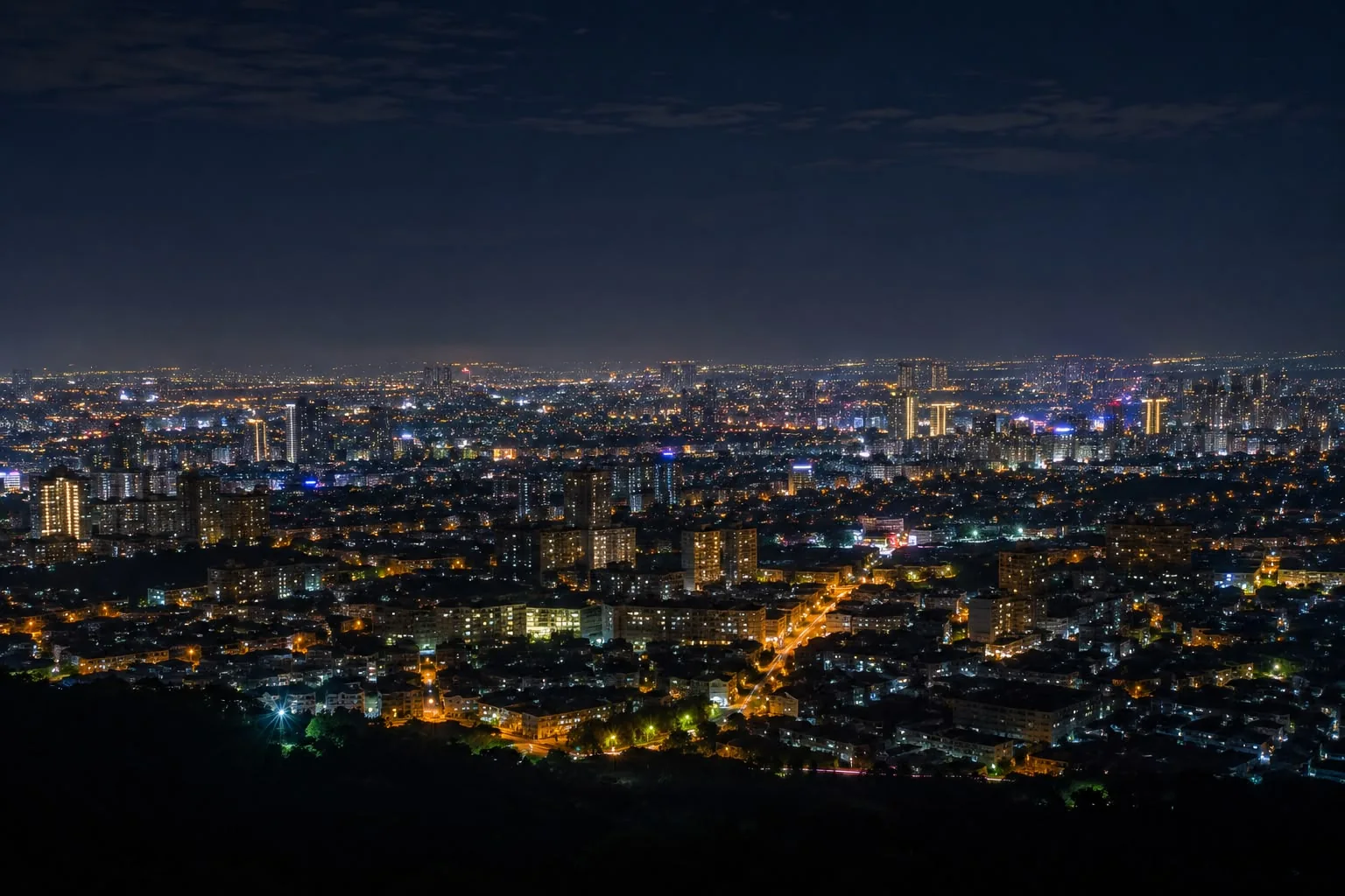 Aerial night view of a densely lit city skyline, representing grid resilience and urban power demand